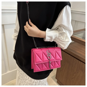 Detail of fuchsia geometric quilted crossbody bag with silver chain strap and tassel
