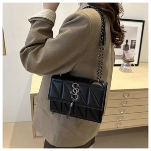 Detail of black quilted leather shoulder bag with silver logo and metal tassel pendant