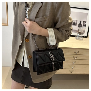 Detail of geometric quilted black leather handbag with silver tassel buckle and chain strap