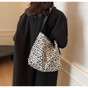 Detail of a leopard print canvas shoulder bag on a model wearing a black winter coat