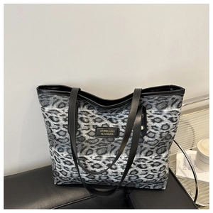 Close-up of leopard print tote bag with leather logo tag and sleek black shoulder straps