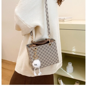 Detail of monogram tote bag with leather trim and cute monster plush pendant charm
