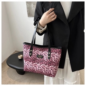 Detail der rosa Leopard-Tragetasche mit schwarzen Kunstlederbesätzen und Goldnieten