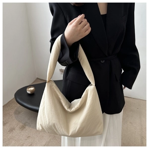 Borsa hobo minimalista in tela color crema indossata con un completo nero molto elegante