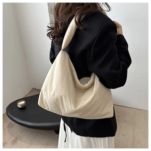 Dettaglio della borsa hobo crema in tessuto testurizzato indossata su un blazer
