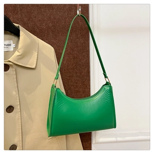 Detail of a bright green faux leather shoulder bag with metallic buckle and zipper