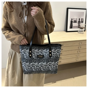 Detail showing leopard print tote bag with black handles and metal rivets in a lifestyle setting