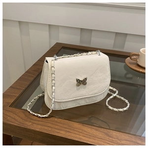Sacoche selle blanche élégante avec fermoir papillon argenté sur une table en bois