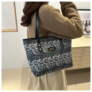 Detail of leopard print tote bag featuring black shoulder straps and gold rivet accents