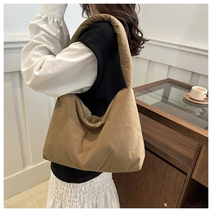Dettaglio di una borsa a spalla imbottita kaki indossata da una modella in stile minimalista