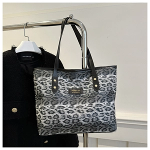 Detail der Leopard-Tasche mit Goldnieten und schwarzen Ledergriffen am Metallkleiderbügel
