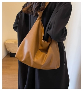 Detail of caramel oversized tote bag featuring knotted strap and pebbled leather texture