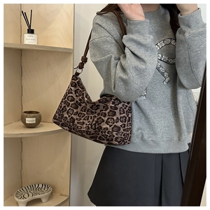 Close-up of leopard print crescent bag with leather knotted shoulder strap detail