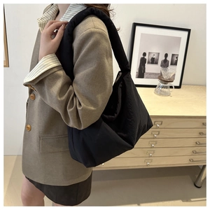 Dettaglio di una borsa tote nera trapuntata indossata da una modella in un interno moderno
