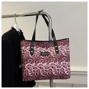 Detail der rosa Tragetasche mit Leopardenmuster, schwarzen Griffen und Markenaufnäher