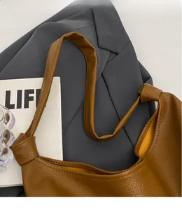 Detail of long shoulder straps with knot design on brown lychee texture tote bag