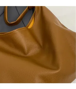 Close-up of brown lychee grain leather tote bag with soft texture and yellow lining
