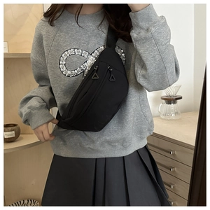 Detail view of a black nylon chest bag with triangle zippers on a gray sweatshirt model