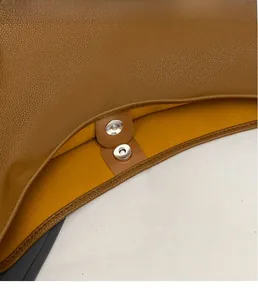Detail of brown litchi pattern leather tote with silver magnetic buckle and yellow lining