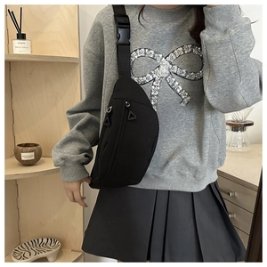 Close-up of minimalist black crescent crossbody bag with adjustable buckle and zipper details