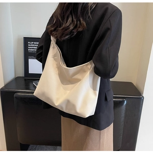 Detailed view of cream-colored tote bag with lychee grain leather and knotted strap