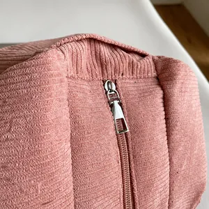 Close-up of smooth silver metal zipper and pink corduroy fabric texture on handbag
