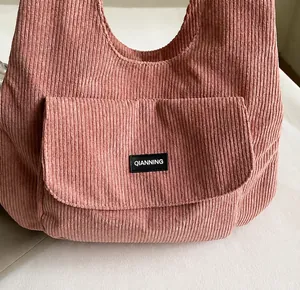 Close-up of pink corduroy tote bag showing textured fabric and black brand label