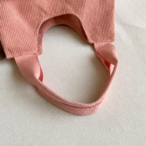 Detailed close-up of pink corduroy fabric and reinforced woven shoulder strap stitching