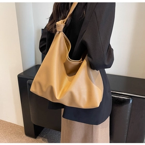 Detailed side view of khaki leather tote bag with knotted strap on model's shoulder