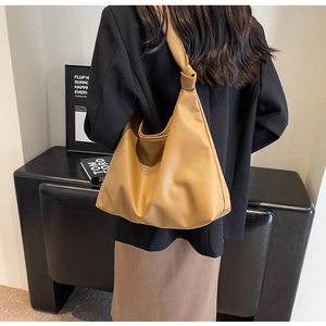 Detail of soft brown pebble leather hobo bag featuring a decorative knotted shoulder strap