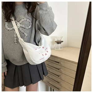 Detailed close-up of white corduroy crescent bag with red fashion letter embroidery