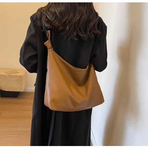 Model view of a brown pebbled leather hobo tote bag with stylish knot strap detail