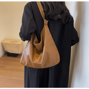 Detail of soft brown pebble leather tote bag with stylish knot strap and crescent shape