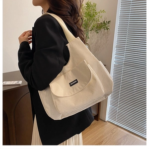 Detail view of cream corduroy tote bag showing front flap pocket and woven brand label