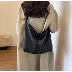 Detail of minimalist black leather hobo bag with knotted shoulder strap texture