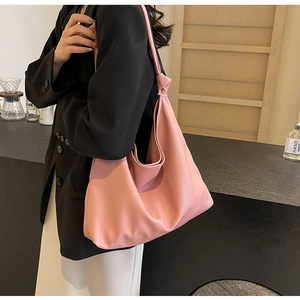 Detail of pink lychee leather tote bag featuring a decorative knot on the shoulder strap