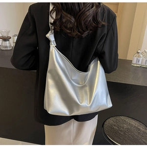 Detail of silver metallic hobo bag featuring a knotted shoulder strap and textured surface