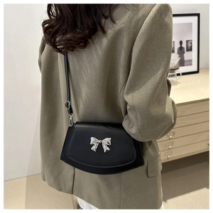 Minimalist black matte leather fan-shaped shoulder bag with silver bow hardware detail