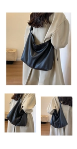 Detail of black pebbled leather tote bag with knotted strap shown on light trench coat