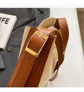 Détail de la boucle dorée brillante et de la bandoulière en cuir marron du sac à main