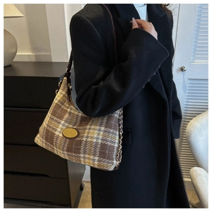 Gros plan d'un sac d'épaule à carreaux vintage avec logo métal et chaîne dorée