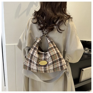 Détail du sac hobo en tweed à carreaux avec logo métallique vintage sur tissu texturé