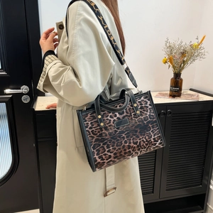 Chic leopard print tote bag with black leather trim and wide geometric shoulder strap