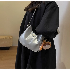 Détail d'un sac hobo argenté avec texte de mode et charm porte-clé en peluche mignon