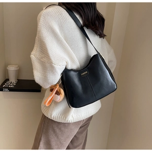 Détail du sac bandoulière en cuir noir avec texte doré et pendentif peluche mignon