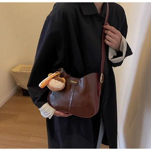 Détail du sac bandoulière en cuir marron avec lettrage FASHION et breloque dessin animé