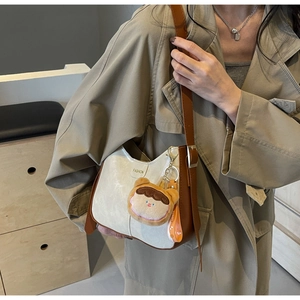 Détail du sac hobo bandoulière beige et marron avec breloque peluche et plaque fashion