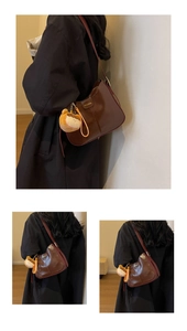 Détail du sac seau en cuir marron avec boucle dorée et breloque ours en peluche