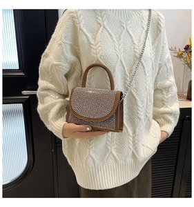 Sac à main marron avec strass porté par un mannequin avec chaîne argentée et poignée