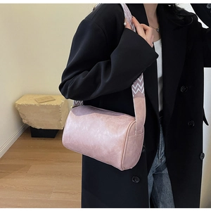 Detail of light pink cylindrical bag with textured leather and patterned wide strap